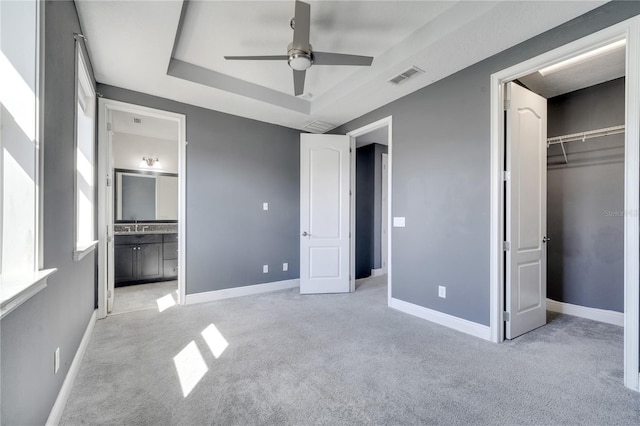 14088 Tarvin St, Orlando, FL 32832 - unfurnished bedroom with light colored carpet, a tray ceiling, ensuite bath, ceiling fan, and a walk in closet