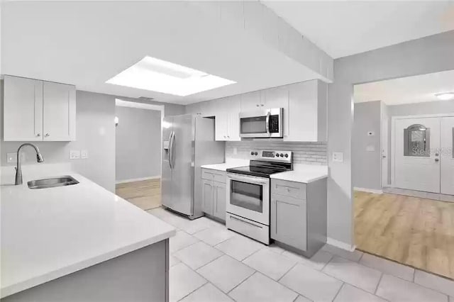 15609 Timberline Dr, Tampa, FL 33624 - kitchen featuring appliances with stainless steel finishes, light countertops, gray cabinetry, tasteful backsplash, and light tile patterned floors