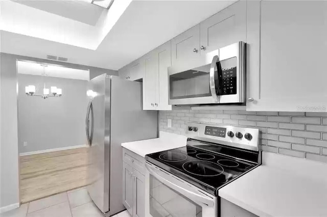 15609 Timberline Dr, Tampa, FL 33624 - kitchen with stainless steel appliances, light countertops, a chandelier, backsplash, and light tile patterned floors