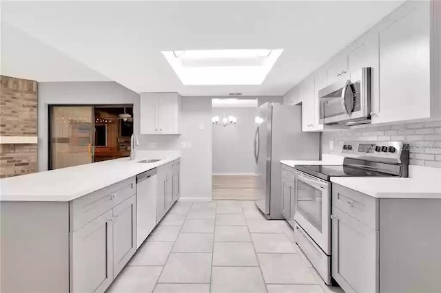 15609 Timberline Dr, Tampa, FL 33624 - kitchen with stainless steel appliances, a peninsula, light tile patterned floors, light countertops, and a chandelier