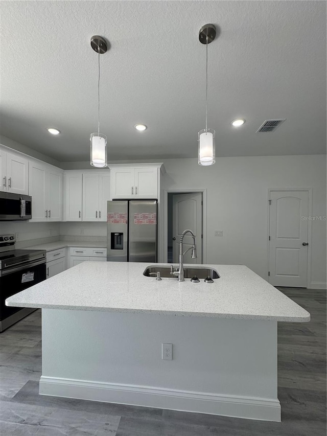 320 W Necho Ave, Lake Alfred, FL 33850 - kitchen with appliances with stainless steel finishes, a kitchen island with sink, white cabinets, a textured ceiling, and light stone countertops
