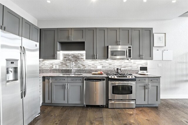 150 E Robinson St Unit 407, Orlando, FL 32801 - kitchen featuring appliances with stainless steel finishes, gray cabinets, backsplash, and light stone countertops