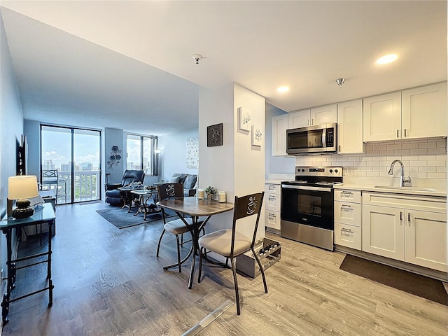 400 E Colonial Dr Unit 1501, Orlando, FL 32803 - kitchen featuring stainless steel appliances, light wood-type flooring, decorative backsplash, floor to ceiling windows, and white cabinetry
