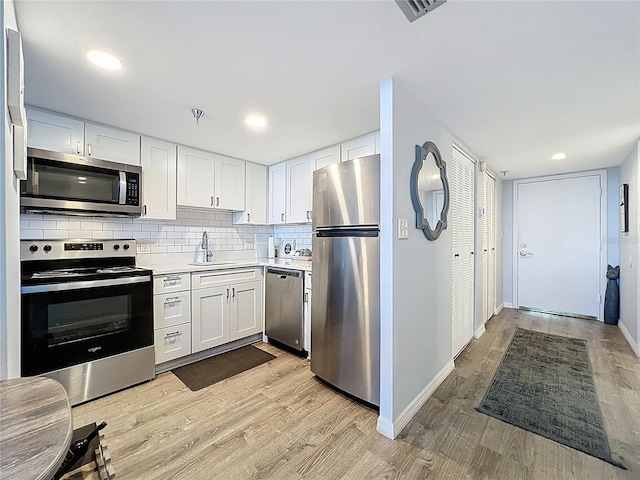 400 E Colonial Dr Unit 1501, Orlando, FL 32803 - kitchen featuring appliances with stainless steel finishes, light countertops, white cabinets, light wood-style floors, and decorative backsplash