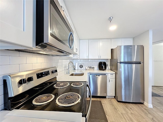 400 E Colonial Dr Unit 1501, Orlando, FL 32803 - kitchen with stainless steel appliances, light wood-style floors, backsplash, light countertops, and white cabinets