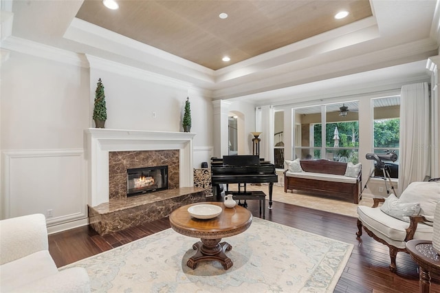25554 Hawks Run Ln, Sorrento, FL 32776 - living room with a raised ceiling, dark wood finished floors, a fireplace, ornate columns, and ornamental molding