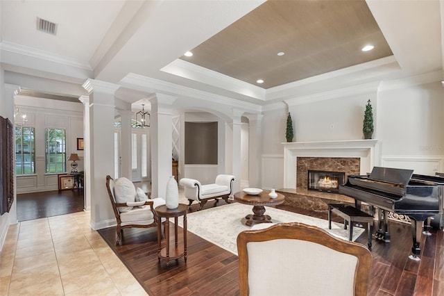 25554 Hawks Run Ln, Sorrento, FL 32776 - living area with ornate columns, a tray ceiling, a high end fireplace, ornamental molding, and light wood-style flooring