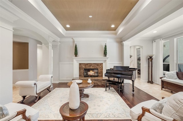 25554 Hawks Run Ln, Sorrento, FL 32776 - living room featuring a tray ceiling, arched walkways, decorative columns, a premium fireplace, and ornamental molding