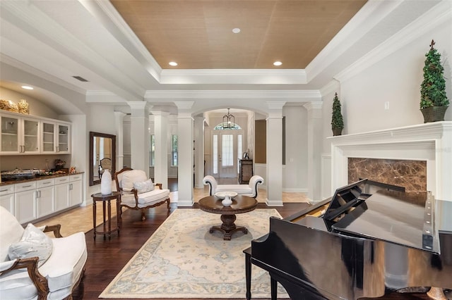 25554 Hawks Run Ln, Sorrento, FL 32776 - living area featuring ornate columns, arched walkways, a tray ceiling, wood finished floors, and crown molding