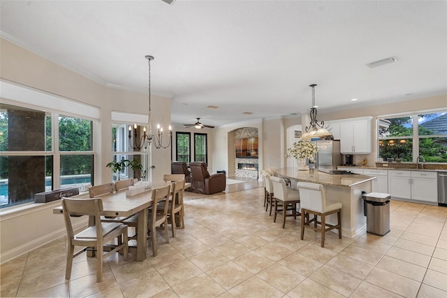 25554 Hawks Run Ln, Sorrento, FL 32776 - dining room featuring light tile patterned flooring, a chandelier, crown molding, a ceiling fan, and arched walkways