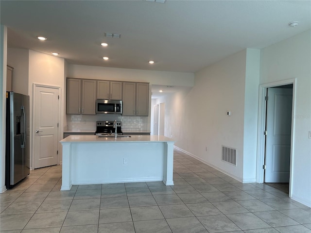 1950 Birnham Wood Bnd, Kissimmee, FL 34746 - kitchen featuring stainless steel appliances, gray cabinets, light countertops, backsplash, and an island with sink