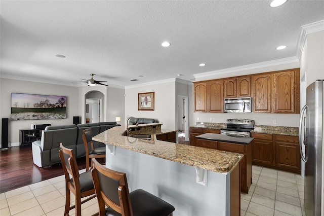 3711 Half Moon Dr, Orlando, FL 32812 - kitchen with stainless steel appliances, an island with sink, light tile patterned flooring, arched walkways, and a breakfast bar area