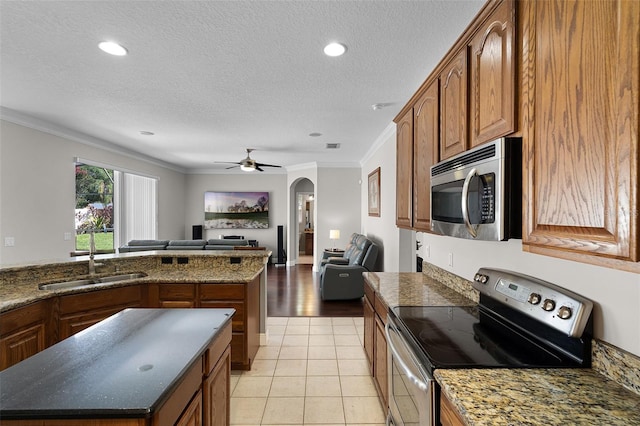 3711 Half Moon Dr, Orlando, FL 32812 - kitchen featuring appliances with stainless steel finishes, open floor plan, crown molding, brown cabinetry, and arched walkways