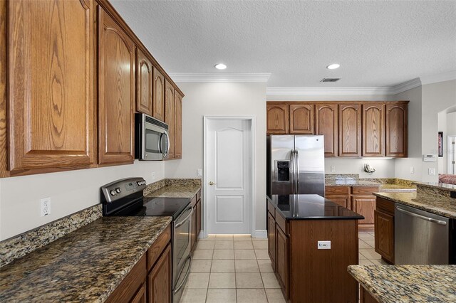3711 Half Moon Dr, Orlando, FL 32812 - kitchen featuring appliances with stainless steel finishes, a center island, light tile patterned floors, a textured ceiling, and dark stone countertops