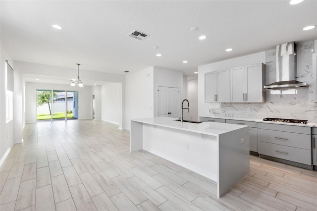 12216 Encore At Ovation Way, Winter Garden, FL 34787 - kitchen featuring wall chimney exhaust hood, gas stovetop, light countertops, recessed lighting, and a center island with sink