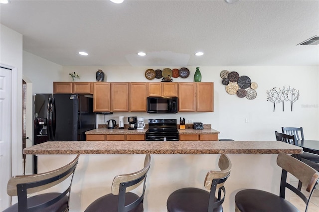 148 Miro Dr, Davenport, FL 33837 - kitchen with black appliances, a breakfast bar area, and recessed lighting