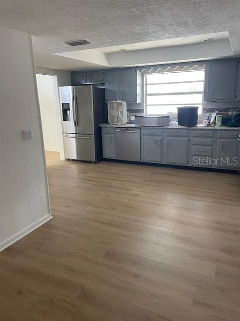 229 Doverwood Rd, Fern Park, FL 32730 - kitchen with appliances with stainless steel finishes, wood finished floors, a decorative wall, a textured ceiling, and gray cabinetry