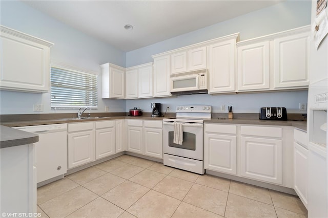 20130 Sunset Landing Ave, Groveland, FL 34736 - kitchen featuring white appliances, light tile patterned floors, white cabinets, and dark countertops
