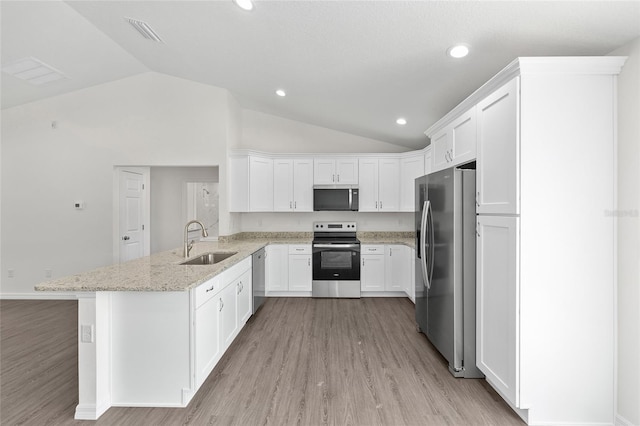 654 NE 130th Ct, Silver Springs, FL 34488 - kitchen with stainless steel appliances, lofted ceiling, a peninsula, light wood finished floors, and white cabinetry
