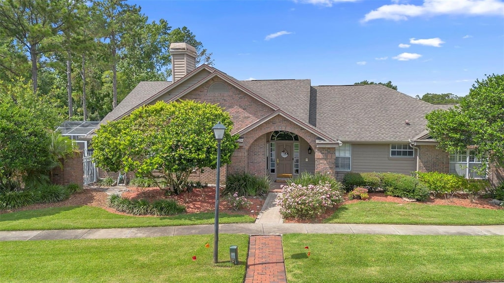 849 Bentley Green Cir, Winter Springs, FL 32708 - traditional home featuring brick siding, a front lawn, and a chimney