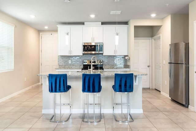 1024 Desert Candle Dr, Ocoee, FL 34761 - kitchen featuring appliances with stainless steel finishes, decorative backsplash, light tile patterned floors, a center island with sink, and recessed lighting