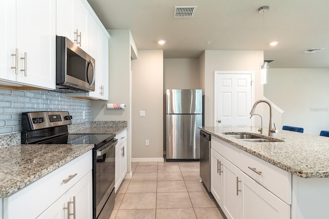 1024 Desert Candle Dr, Ocoee, FL 34761 - kitchen featuring stainless steel appliances, decorative backsplash, light stone counters, light tile patterned floors, and white cabinetry