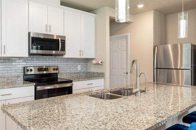 1024 Desert Candle Dr, Ocoee, FL 34761 - kitchen with appliances with stainless steel finishes, tasteful backsplash, light stone countertops, white cabinets, and an island with sink