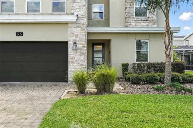 369 Ocean Course Ave, Davenport, FL 33896 - doorway to property featuring stone siding, an attached garage, stucco siding, driveway, and a yard