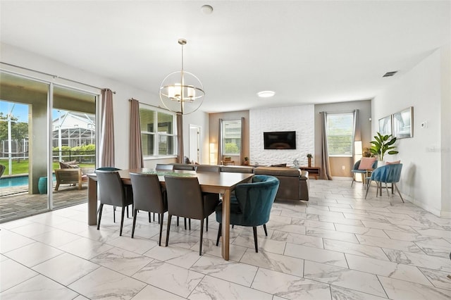369 Ocean Course Ave, Davenport, FL 33896 - dining room featuring light marble finish floors, a chandelier, healthy amount of natural light, and a fireplace