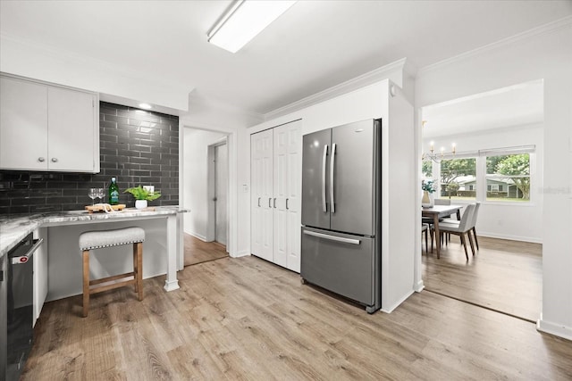 1505 N Lake Mirror Dr NW, Winter Haven, FL 33881 - kitchen with freestanding refrigerator, crown molding, a chandelier, light wood-style flooring, and decorative backsplash