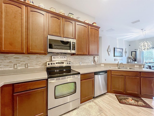 725 Ashworth Overlook Dr Unit C, Apopka, FL 32712 - kitchen with stainless steel appliances, decorative backsplash, a chandelier, light countertops, and light wood-type flooring