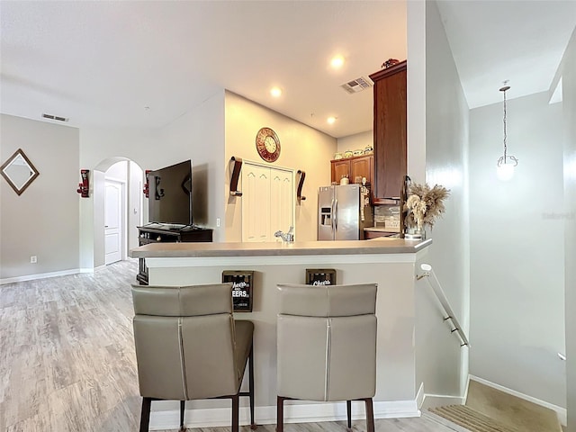 725 Ashworth Overlook Dr Unit C, Apopka, FL 32712 - kitchen featuring stainless steel fridge with ice dispenser, brown cabinets, arched walkways, a peninsula, and light wood finished floors