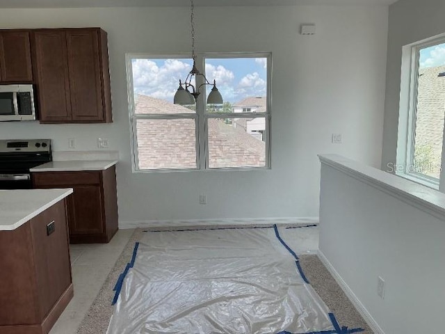2971 Embark Trl, Saint Cloud, FL 34771 - kitchen with stainless steel appliances, light countertops, a chandelier, and dark brown cabinets