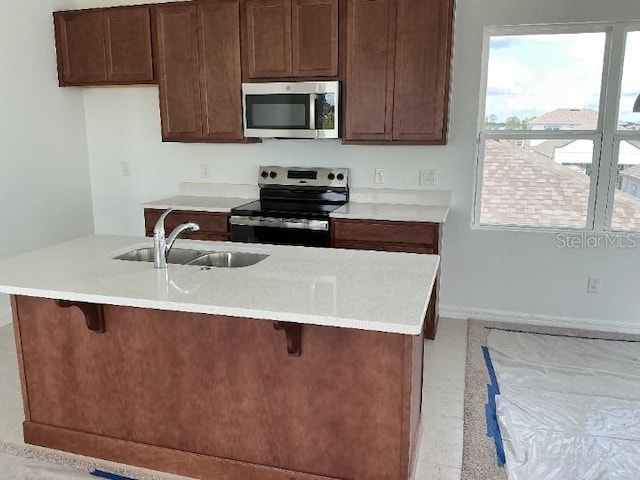 2971 Embark Trl, Saint Cloud, FL 34771 - kitchen featuring stainless steel appliances, light countertops, a kitchen bar, and a kitchen island with sink