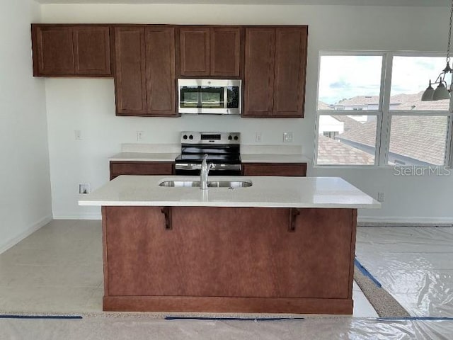 2971 Embark Trl, Saint Cloud, FL 34771 - kitchen with appliances with stainless steel finishes, light countertops, a breakfast bar, dark brown cabinets, and a center island with sink