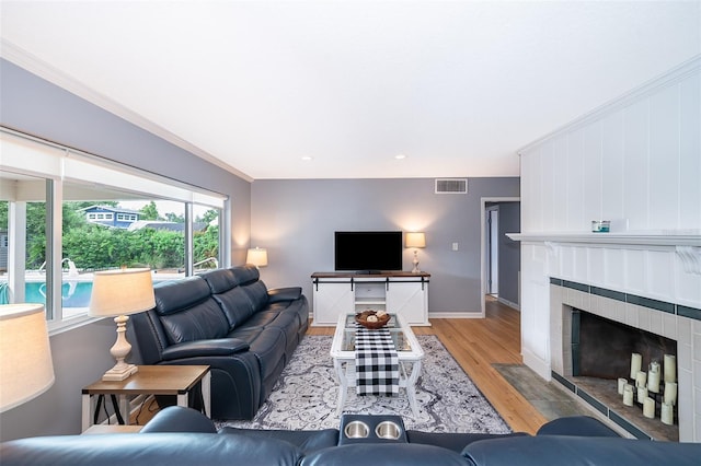 1301 Fahnstock St, Eustis, FL 32726 - living room featuring light wood-style floors, crown molding, a tiled fireplace, and recessed lighting