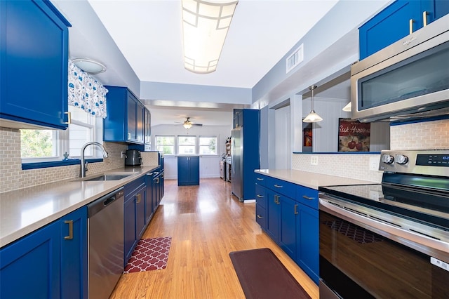 1301 Fahnstock St, Eustis, FL 32726 - kitchen with stainless steel appliances, blue cabinetry, decorative backsplash, and light wood finished floors