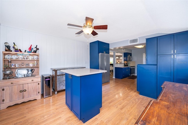 1301 Fahnstock St, Eustis, FL 32726 - kitchen featuring blue cabinetry, appliances with stainless steel finishes, a ceiling fan, light wood-type flooring, and a center island