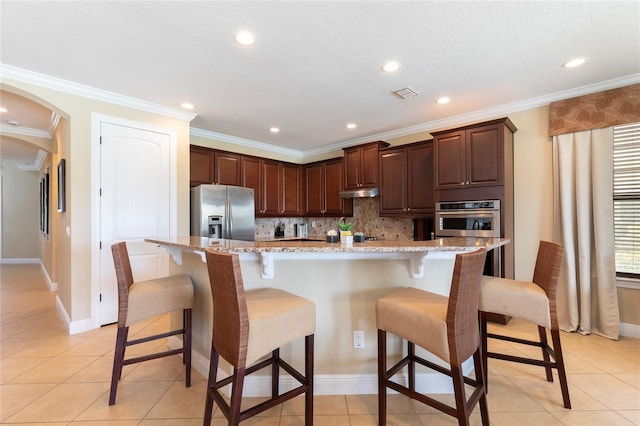 1156 Castle Pines Ct, Reunion, FL 34747 - kitchen featuring stainless steel fridge with ice dispenser, decorative backsplash, arched walkways, under cabinet range hood, and a breakfast bar area