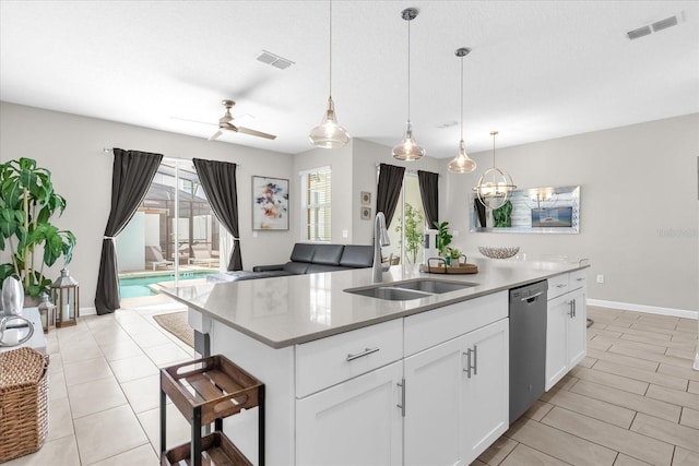4802 Lullaby Ln, Kissimmee, FL 34746 - kitchen featuring stainless steel dishwasher, a kitchen island with sink, white cabinets, hanging light fixtures, and light countertops
