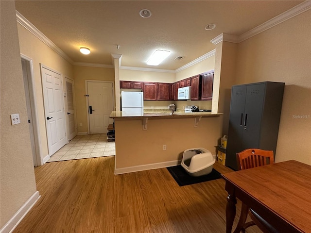 1370 Tuscan Ter Unit 2202, Davenport, FL 33896 - kitchen featuring white appliances, a peninsula, light wood-style flooring, a kitchen breakfast bar, and ornamental molding