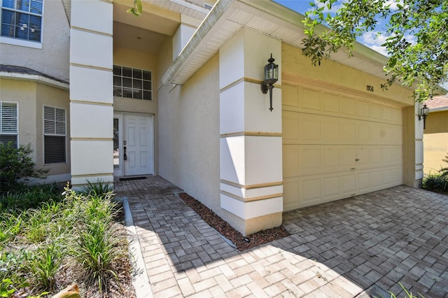 1936 Westpointe Cir, Orlando, FL 32835 - view of exterior entry with a garage, stucco siding, and decorative driveway