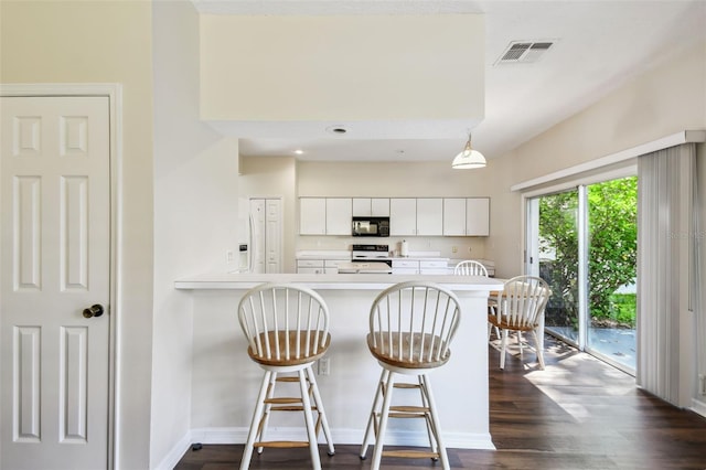 1936 Westpointe Cir, Orlando, FL 32835 - kitchen with black microwave, light countertops, white cabinets, a kitchen bar, and range with electric stovetop