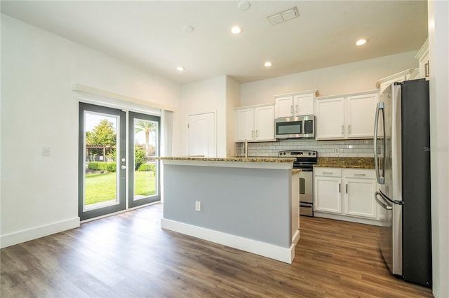 11081 Savannah Landing Cir, Orlando, FL 32832 - kitchen featuring appliances with stainless steel finishes, tasteful backsplash, white cabinetry, dark wood finished floors, and recessed lighting
