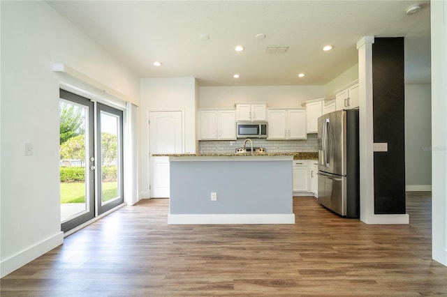 11081 Savannah Landing Cir, Orlando, FL 32832 - kitchen with appliances with stainless steel finishes, white cabinetry, tasteful backsplash, a center island with sink, and recessed lighting