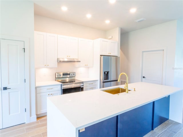 14073 Naylor Ave, Port Charlotte, FL 33981 - kitchen with stainless steel appliances, under cabinet range hood, a kitchen island with sink, white cabinetry, and wood tiled floors