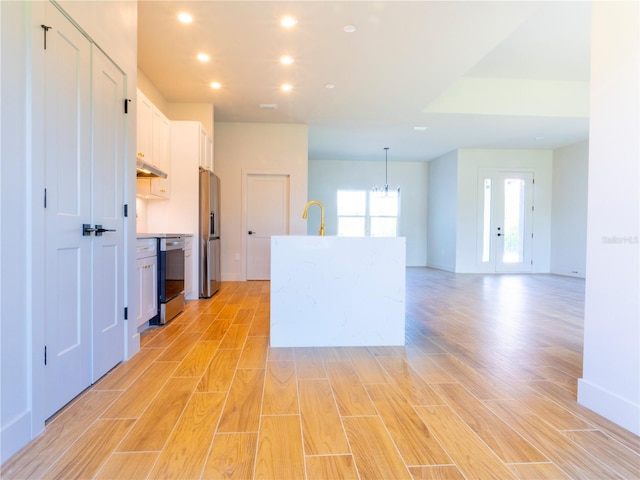 14073 Naylor Ave, Port Charlotte, FL 33981 - kitchen featuring appliances with stainless steel finishes, white cabinets, light wood-type flooring, recessed lighting, and a center island with sink