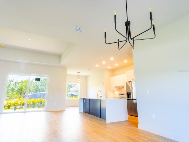 14073 Naylor Ave, Port Charlotte, FL 33981 - kitchen featuring stainless steel fridge with ice dispenser, a chandelier, light countertops, a center island with sink, and light wood-type flooring