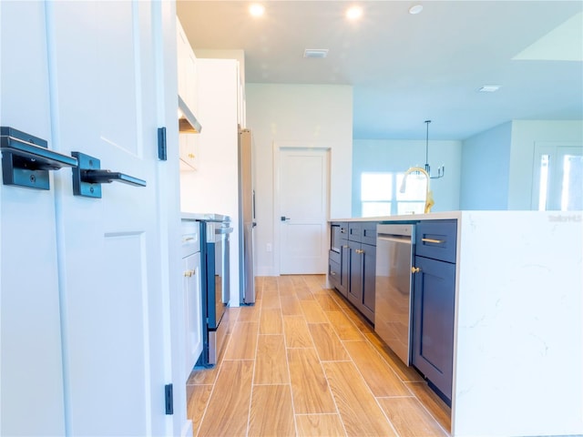 14073 Naylor Ave, Port Charlotte, FL 33981 - kitchen with stainless steel dishwasher, wood finish floors, white cabinetry, range, and decorative light fixtures