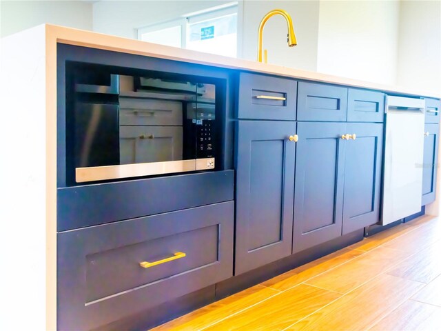 14073 Naylor Ave, Port Charlotte, FL 33981 - detailed view of stainless steel microwave, light wood-style flooring, and blue cabinets